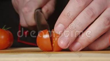 厨师在厨房的切割板上切一个樱桃番茄